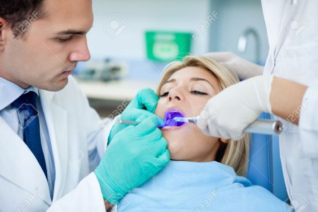 16217437-patient-with-open-mouth-receiving-dental-filling-drying-procedure--Stock-Photo